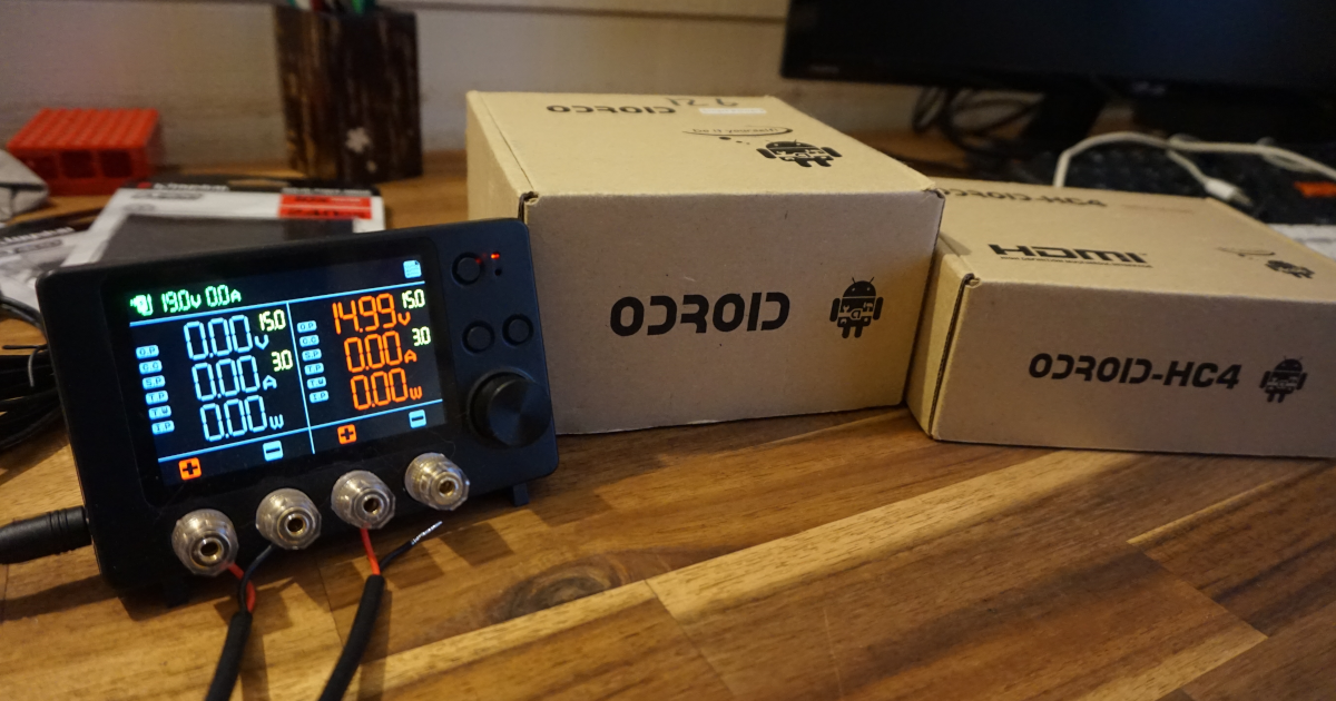 A wattmeter (SmartPower 3) next to two Odroid boxes on a wooden desk.